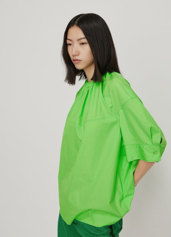 junge Frau in grüner Ballon-Bluse von JNBY; Seitansicht Links